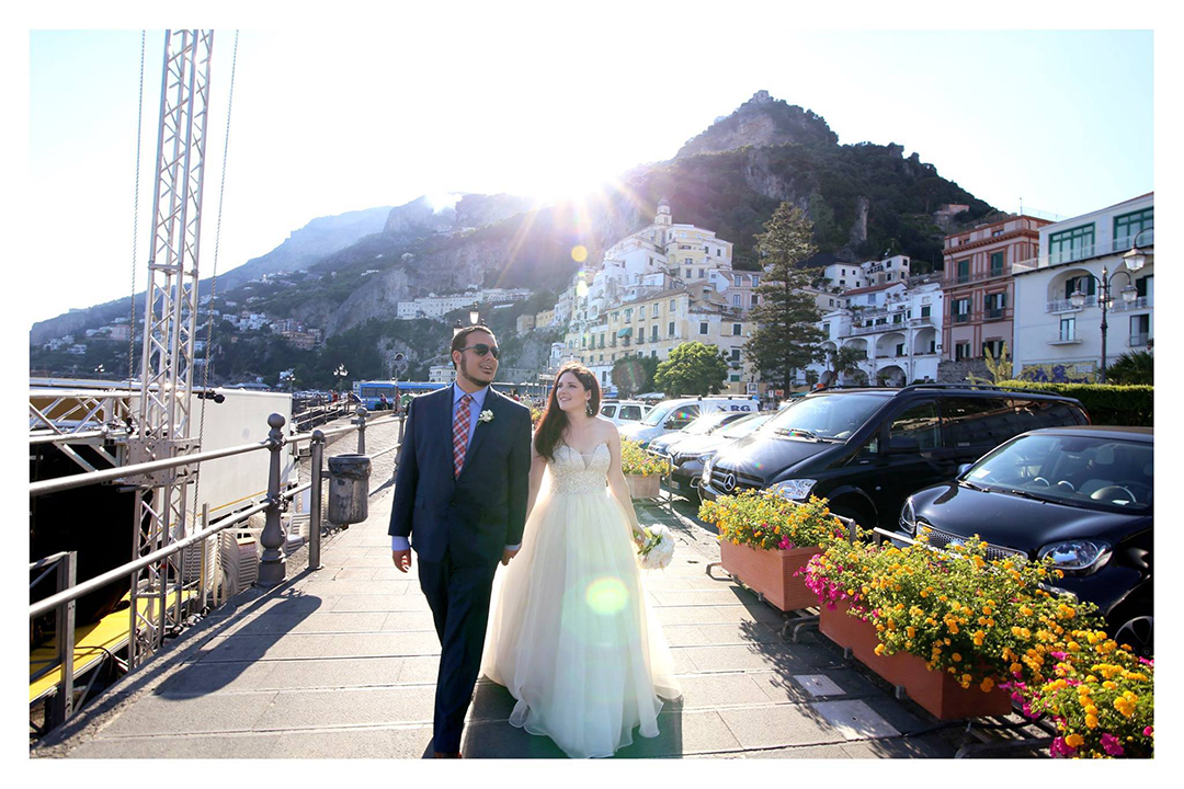 bride and groom walking down coast of italy