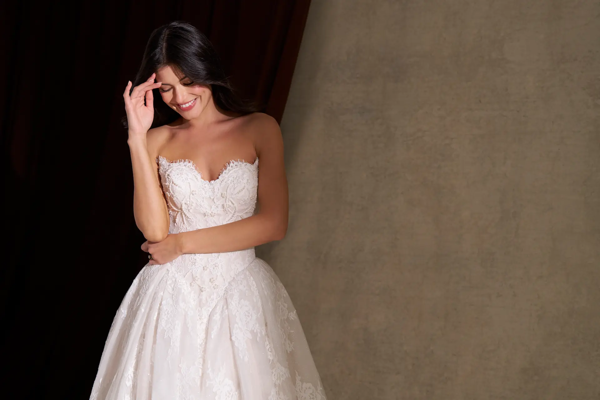 Model wearing the Allure Bridals C845 wedding dress with a strapless sweetheart neckline, beaded lace bodice, basque waist and full lace ball gown skirt.