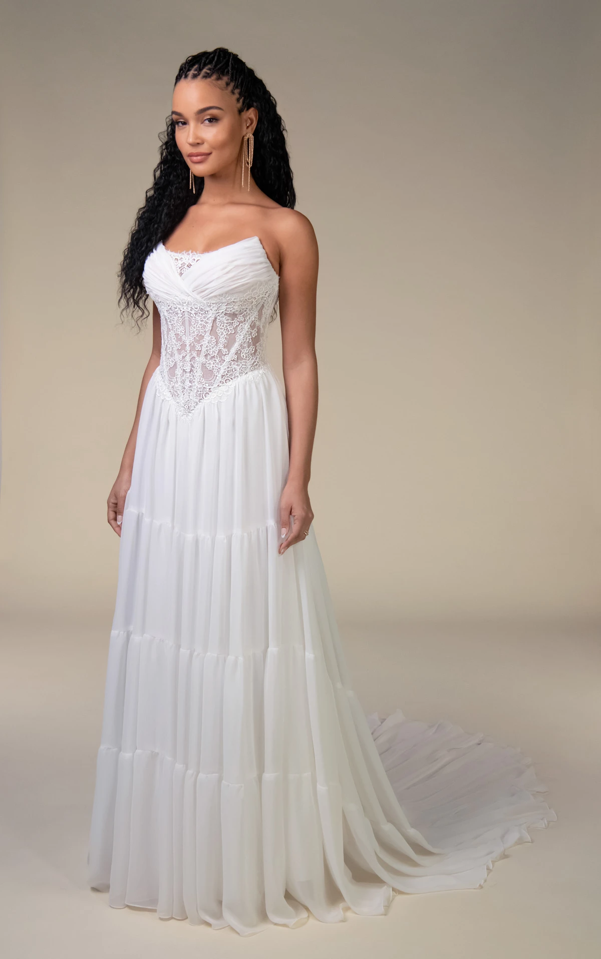 Model wearing the All Who Wander Dalton wedding dress, featuring a strapless lace corset bodice and flowing chiffon A-line skirt with tiered detailing.