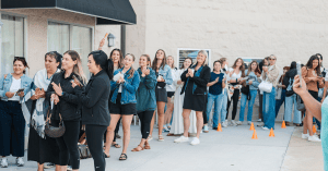 A long line of enthusiastic brides and guests clapping and waiting outside the building entrance during the National Bridal Sale Day at The Bridal Collection.