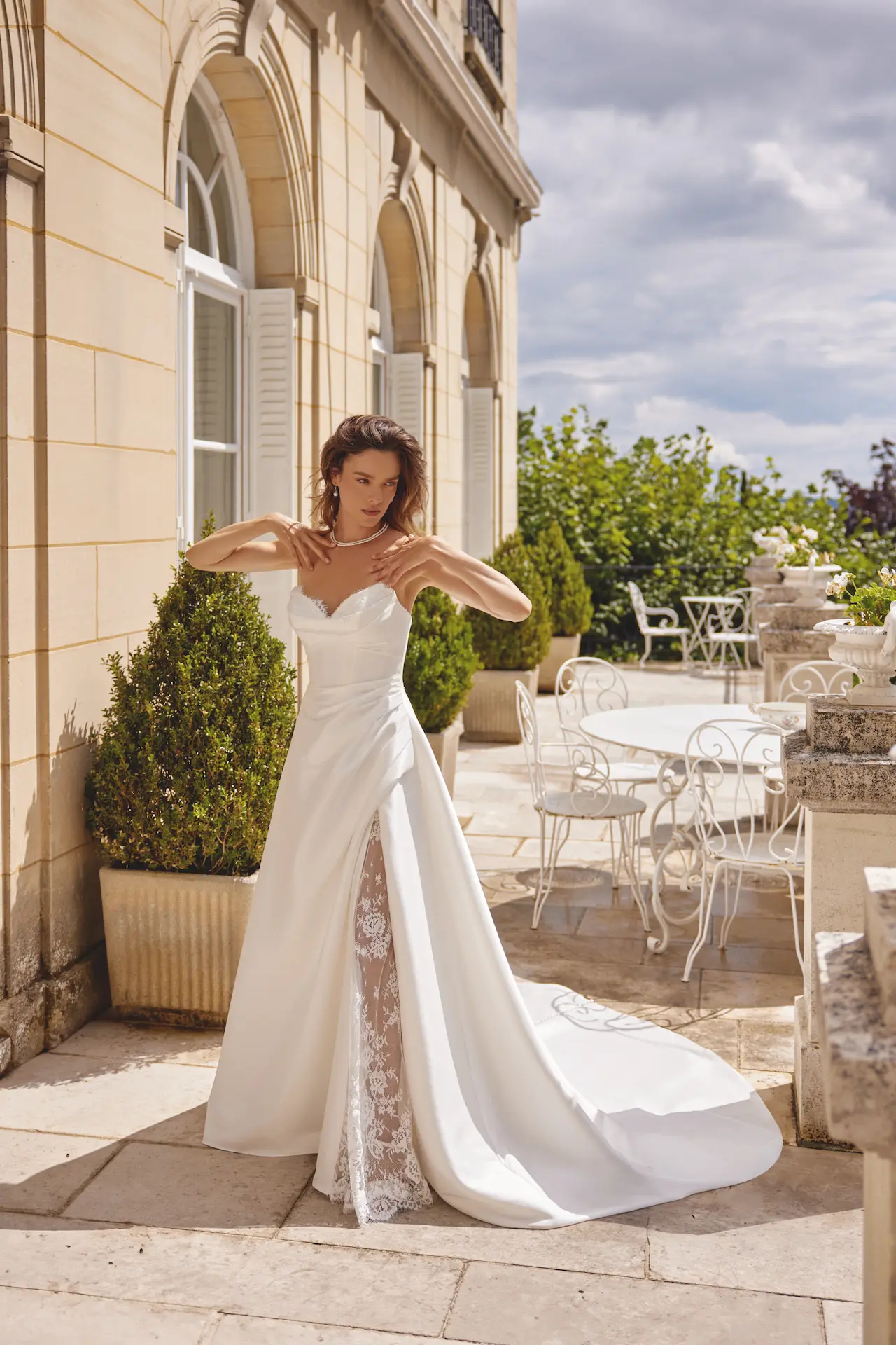 Model wearing the Justin Alexander Madison wedding dress with a strapless ruched bodice, Mikado A-line skirt and high slit with lace detailing, available at The Bridal Collection in Denver, Colorado.